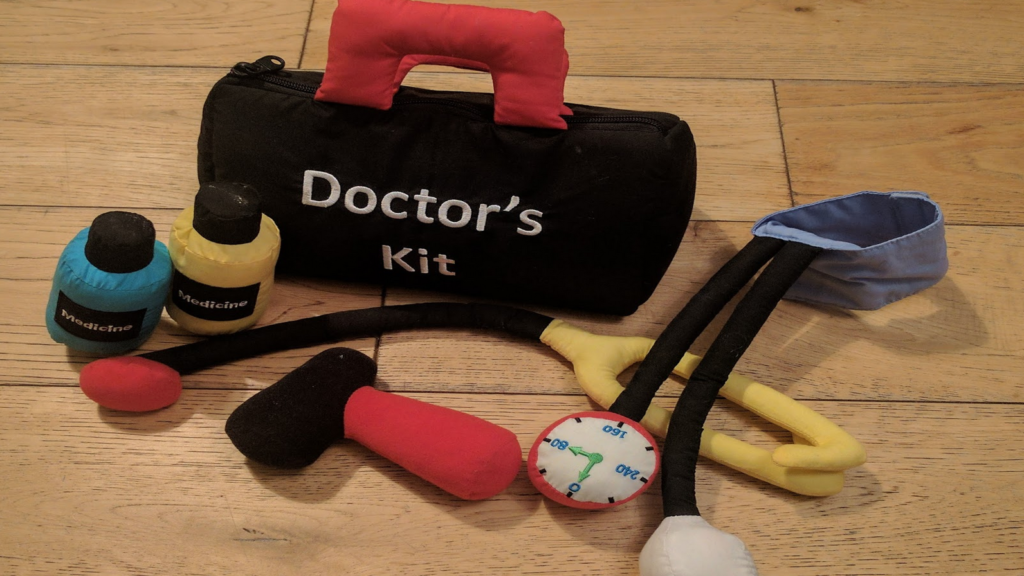 Photo of a children's toy "doctor's kit": bag, medicines, hammer, stethoscope, blood pressure pump. All are made from soft-toy materials.