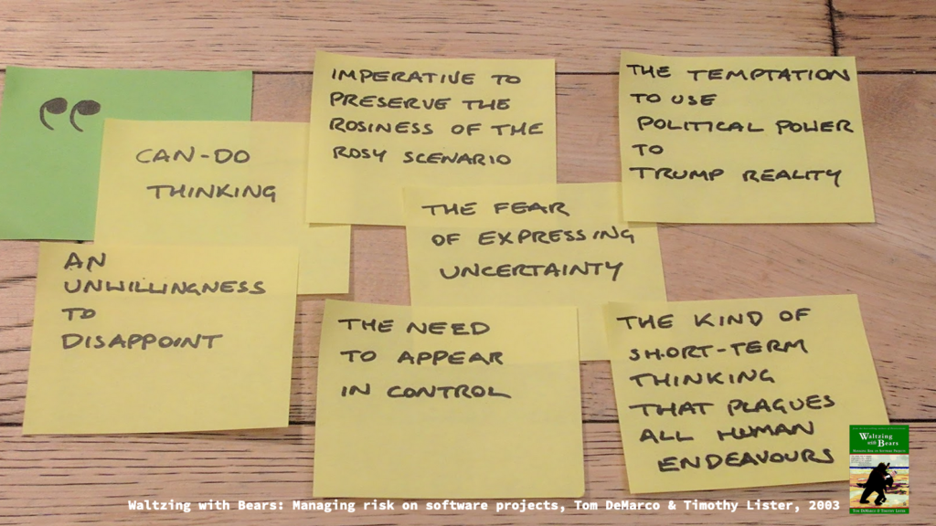 Post-its on a wooden floor, with a long quote:

"Can do thinking" 
"An unwillingness to disappoint"
"Imeperative to preserve the rosiness of the rosy scenario"
"The fear of expressing uncertainty"
"The need to appear in control"
"The temptation to use political power to trump reality"
"The kind of short-term thinking that plagues all human endeavours"

Typed text along the bottom has the source: "Waltzing with Bears: Managing risk on software projects, Tom DeMarco & Timothy Lister, 2003"
