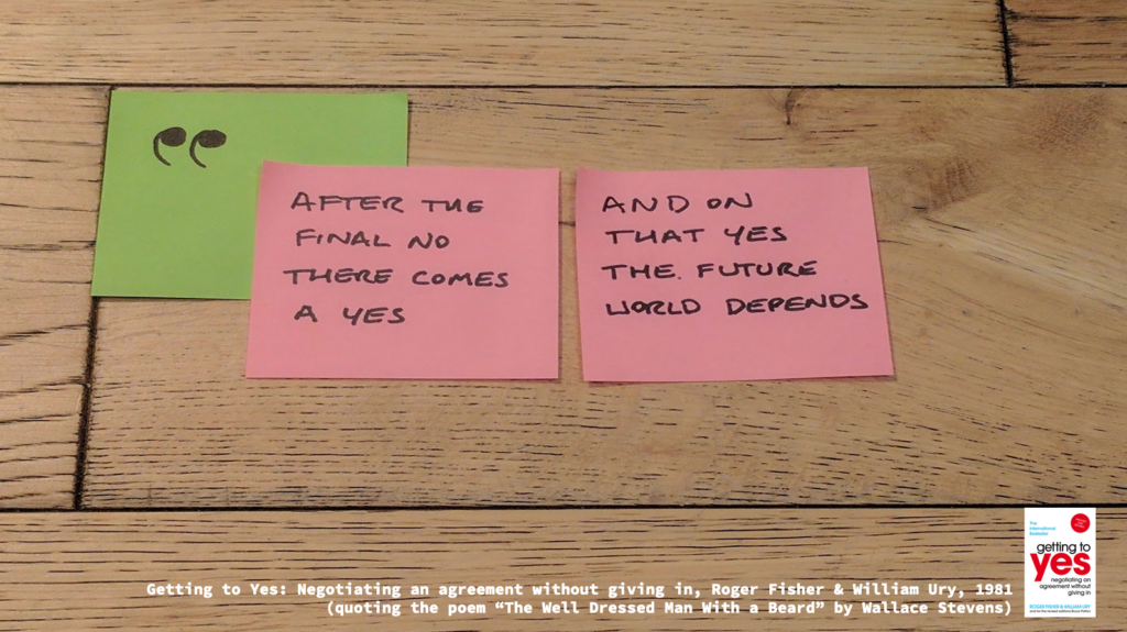Post-its with a quote:
"After the final no there comes a yes"
"And on that yes the future world depends"

Typed at the bottom, the source: "Getting to Yes: Negotiating an agreement without giving in, Roger FIsher & William Ury, 1981 (quoting the poem "The Well Dressed Man With a Beard" by Wallace Stevens)"