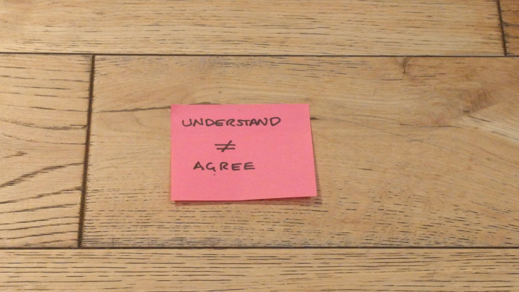 Post-it on a floor, with "understand", a "not equal to" symbol, and "agree".