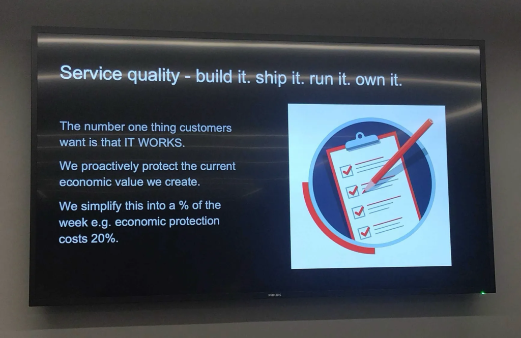 Photo of slide:
Service quality - build it. ship it. run it. own it. The number one thing customers want is that IT WORKS. We proactively protect the current economic value we create. We simplify this into a % of the week e.g. economic protection costs 20%.

It's a black slide with white writing, and a large illustration of items getting ticked on a clipboard.