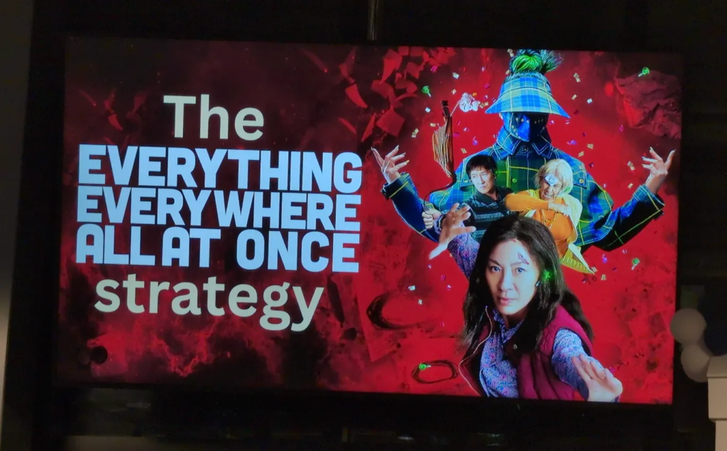 Slide based on the movie poster for "Everything everywhere all at once", labelled "The everything everywhere all at once strategy". It has various movie characters in dramatic poses.