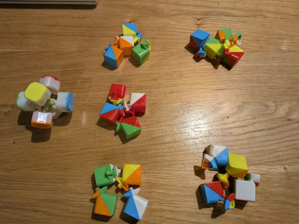 The same disassembled cube as before, more neatly arranged. There are 3 groups of 4 edge pieces (2 colours each), and 2 groups of 4 corner pieces (3 colours each).