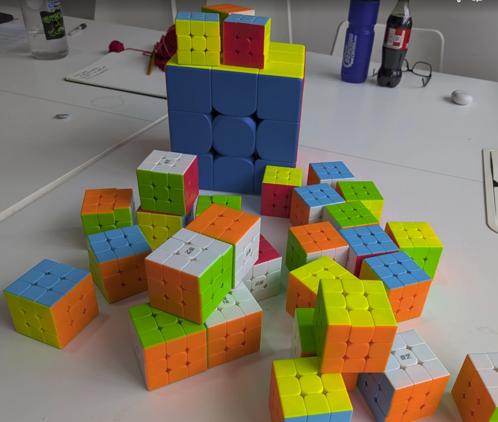 Photo of one big cube and a about 25 little ones haphazardly arranged in front and on top of it.
