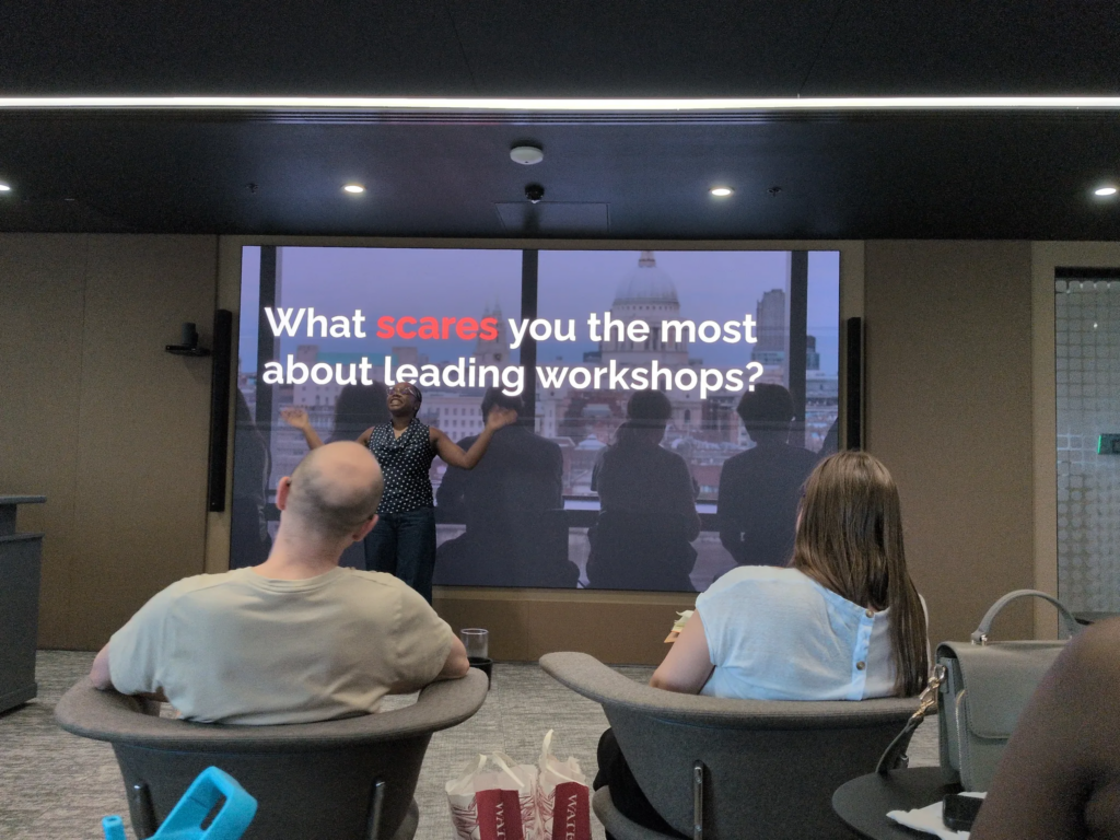 Annie in front of the huge screen, where her slide asks: What scares you the most about leading workshops?